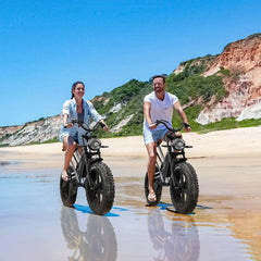JANSNO X50 electric bikes in black, side view, ridden on a sandy beach