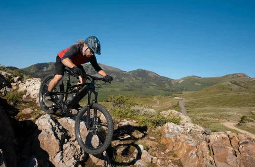 Electric mountain bike with rider on rocky trail, side view, outdoor landscape