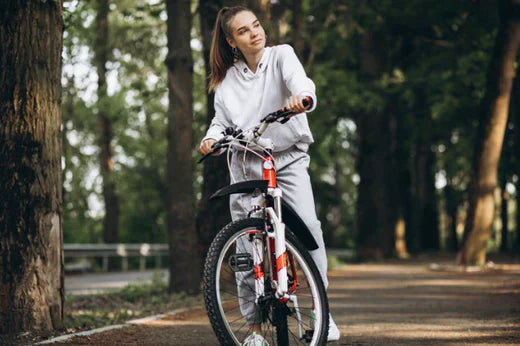 Woman with red and white electric bike on forest path, front side view
