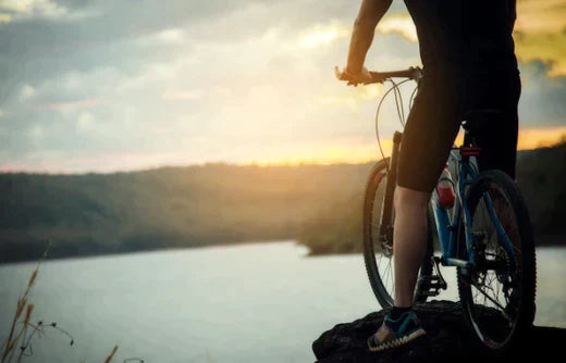 Electric bike with rider overlooking a lake at sunset, side view, outdoor setting