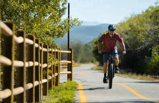 Electric bike ridden by man on a scenic paved trail, front view, casual outdoor setting