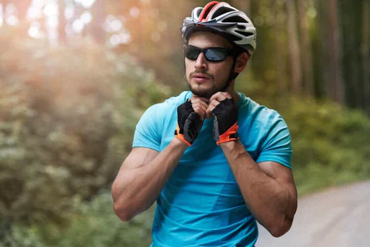 Cyclist securing helmet strap while wearing sunglasses on forest road