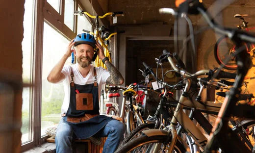 Man puts on bike helmet beside multiple electric bikes in indoor shop setting