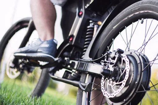 Close-up of electric bike rear wheel, motor, and disc brake outdoors
