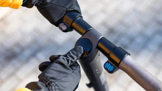 Close-up of electric bike handlebar and display with gloved hand pressing the power button