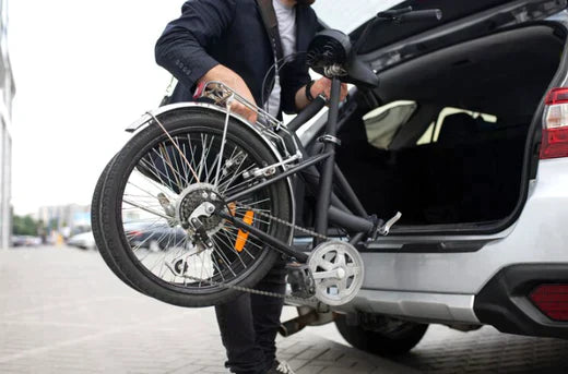 Folding electric bike in black being loaded into a car trunk, side view on street