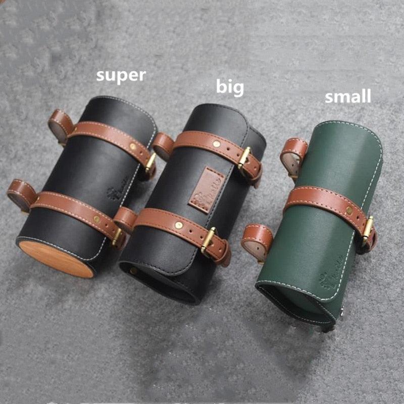 Three handmade leather bicycle saddle bags in different sizes (super, big, small) displayed on a grey surface, featuring brown straps and stitching – Pogo Cycles.
